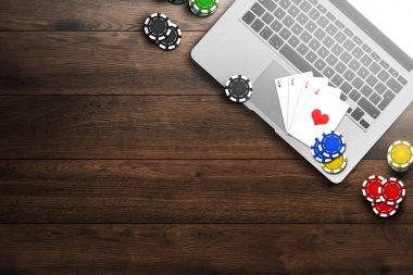 Online casino, dizüstü bilgisayar, cips kartları ahşap arka plan üzerinde. Kumar. Yukarıdan görüntülemek.