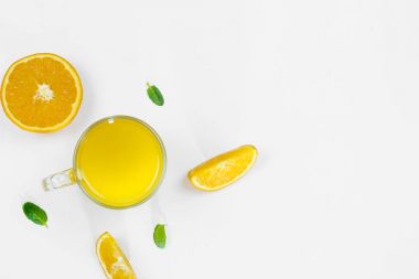 Kesilmiş portakal, dilimleri, nane yaprağı, beyaz bir arka planda, düz cam üst görünümünde portakal suyu yatıyordu. Sağlıklı, doğru beslenme, ditox kavramı.