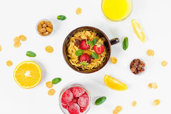 Cereal, morning breakfast, corn flakes, raisins, almonds, mint leaves, orange juice, strawberry, top view, white background, flat lay. The concept of healthy, proper nutrition, ditox.