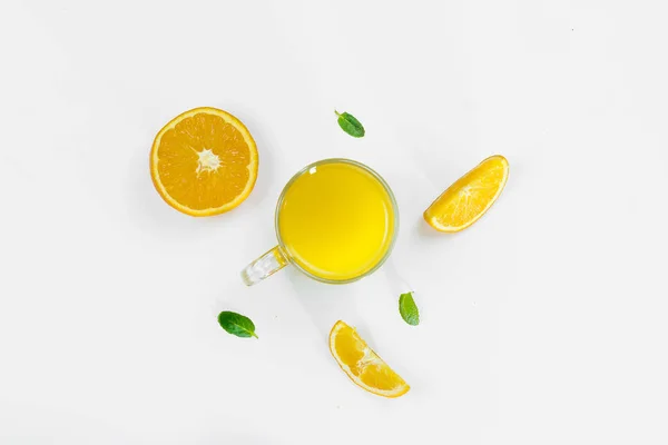 Cut orange, slices, mint leaves, orange juice in a glass top view on a white background, flat lay. The concept of healthy, proper nutrition, ditox. — Stock Photo, Image