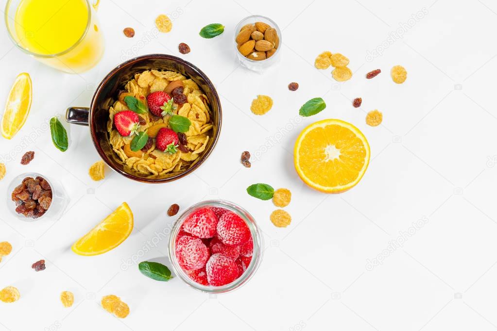 Cereal, morning breakfast, corn flakes, raisins, almonds, mint leaves, orange juice, strawberry, top view, white background, flat lay. The concept of healthy, proper nutrition, ditox.