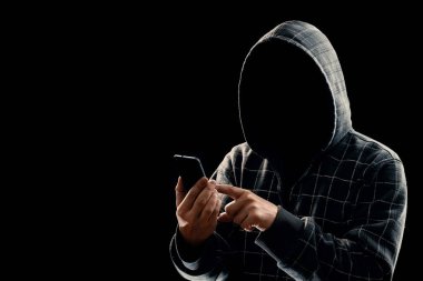 Siluet siyah bir arka plan, yüzünü bir kaputa bir adamın görünür değil, hacker telefon elinde tutuyor. Bir suçlu, gizli, gizem, gizlilik, gizlilik kavramı.