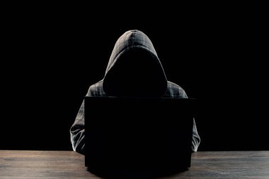 Siluet siyah bir arka plan, yüzünü bir kaputa bir adamın görünür değil, bilgisayar başında oturuyor. Bir suçlu, gizli, gizem, gizlilik, gizlilik kavramı.