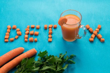 Yazıt Detoks, üstten görünüm, mavi bir arka plan üzerine bir bardak havuç suyu. Sağlıklı bir diyet, diyet kavramı.