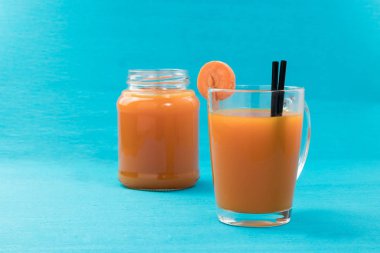 Mavi bir arka plan üzerine bir bardak havuç suyu yakın çekim. Sağlıklı bir diyet, diyet kavramı.