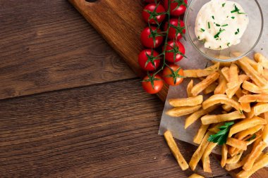 Kızarmış patates, domates, sarımsak sosu bir ahşap kahverengi zemin üzerinde görünümü top.