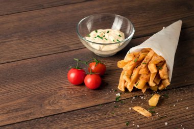 Patates kızartması, kahverengi ahşap arka plan, bir kağıt torbaya yakın çekim.