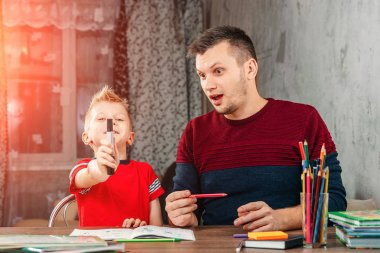 Baba oğlu ödev yapmak için yardımcı olur.