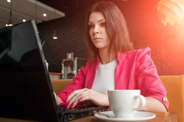 Νέους, όμορφο κορίτσι, επιχειρηματίας, κάθονται στο καφέ και να εργάζονται στο lap-top. επαγγελματικό γεύμα, φλιτζάνι καφέ, επιτυχημένη γυναίκα. — Φωτογραφία Αρχείου