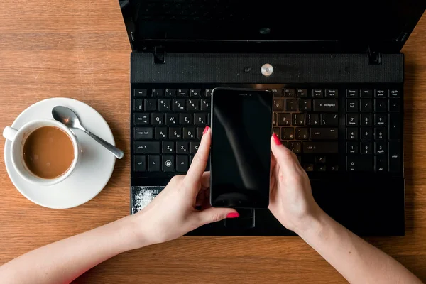 Manos femeninas con teléfono en el fondo del portátil. maqueta — Foto de Stock