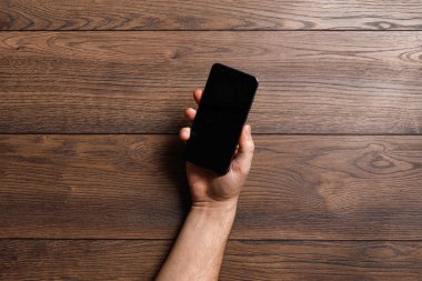Ahşap bir masa üzerinde bir smartphone kullanarak eller. kopya alanı