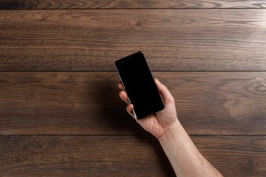 Ahşap bir masa üzerinde bir smartphone kullanarak eller. kopya alanı
