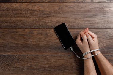 Yakın çekim, ellerini bir adamın smartphone için bir kablo ile bağlı. Kavram teknoloji, telefon, sosyal ağlar, bir blogger üzerinde bağlıdır. kopya alanı