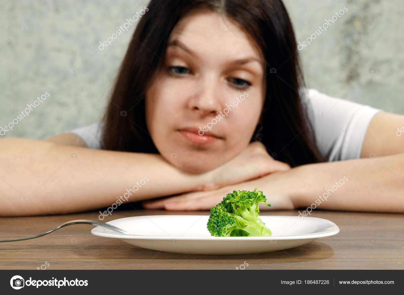 Sad Young Brunette Woman Dealing With Anorexia Nervosa Or Bulimia Sad Young Brunette Woman Dealing With Anorexia Nervosa Or Bulimia Having Small Green Vegetable On Plate