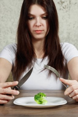 Anoreksiya Nervoza ya da küçük yeşil sebze plaka üzerinde sahip bulimia ile ilgili üzgün genç esmer kadın. Diyet sorunları, yeme bozukluğu.