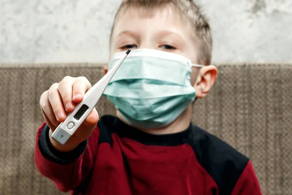 少年のポートレート、医療マスクの子は彼の手で温度計を保持しています。病、インフルエンザの子供、結核、免疫、病気からの保護の概念. — ストック写真