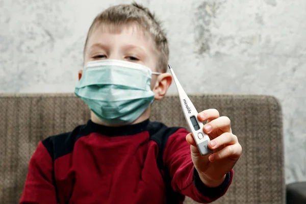 一个男孩的肖像, 一个戴着口罩的孩子, 手里拿着温度计。疾病的概念, 儿童的流感, 肺结核, 免疫力, 疾病的保护. — 图库照片