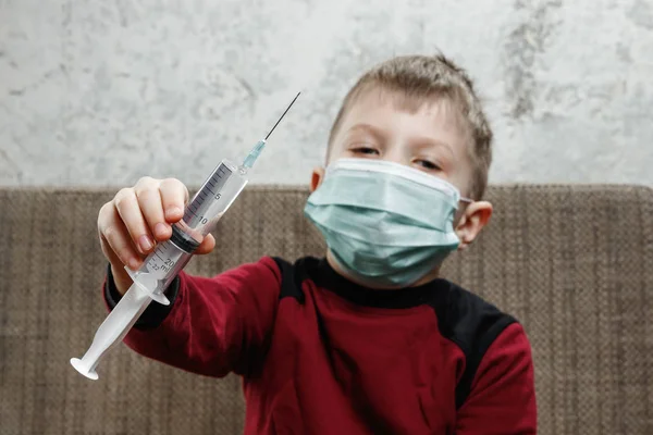 少年のポートレート、医療マスクの子は彼の手で注射器を保持しています。病、インフルエンザの子供、結核、免疫、病気からの保護の概念. — ストック写真