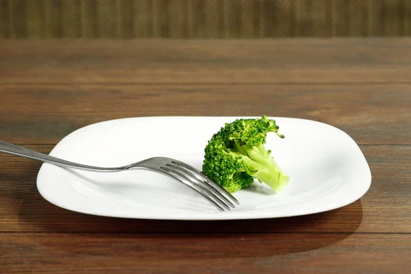 Photo of the fork with white plate and broccoli on wood table. The concept of a healthy diet, detox, weight loss, diet, eating problems, anorexia, bulimia. — Stock Photo, Image