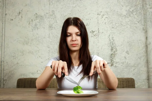 Triste joven morena que trata con anorexia nerviosa o bulimia que tiene pequeña verdura verde en el plato. Problemas de dieta, trastorno alimentario . — Foto de Stock