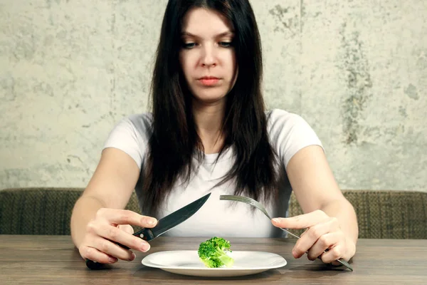 Szomorú fiatal barna nő foglalkozik az anorexia nervosa vagy a bulimia, miután kis zöld növényi lemez. Fogyókúra problémák, étkezési rendellenesség. — Stock Fotó