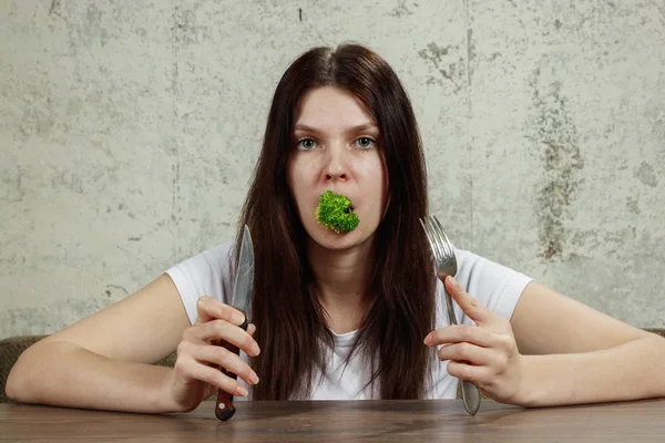 Retrato de una joven y hermosa niña sosteniendo un brócoli en su boca.. El concepto de una dieta saludable, desintoxicación, pérdida de peso, dieta, problemas de alimentación, anorexia, bulimia . — Foto de Stock