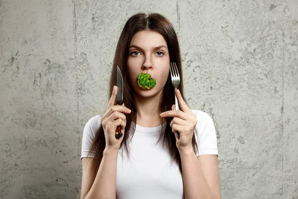 Portrait d'une jeune, belle fille tenant un brocoli dans sa bouche.. Le concept d'une alimentation saine, désintoxication, perte de poids, alimentation, problèmes alimentaires, anorexie, boulimie . — Photo