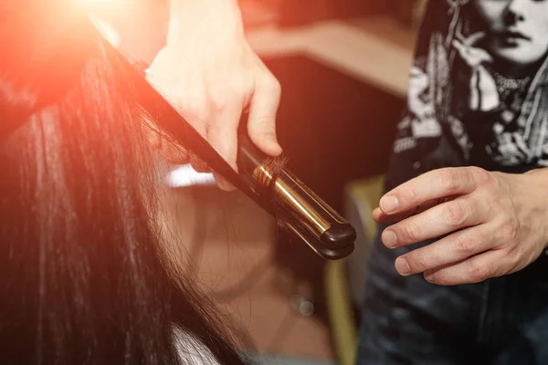 Close-up de mãos estilistas com ferro styling alisamento cabelo da mulher no salão — Fotografia de Stock