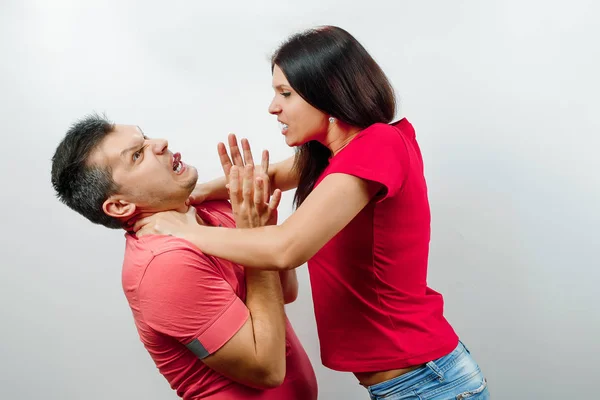 A family quarrel, his wife scolds her husband, a young, beautiful wife strangling her husband. The concept of the psychology of family relations, marriage, domestic conflicts, domestic violence. — Stock Photo, Image
