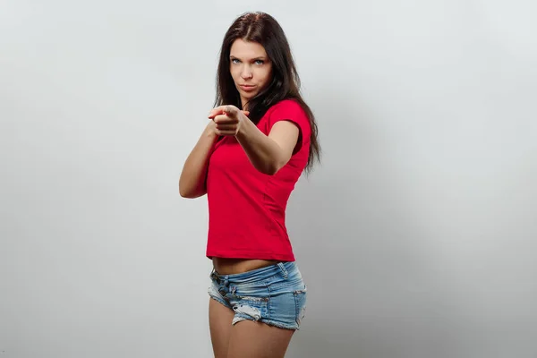 Ein junges, schönes Mädchen zeigt eine Geste mit ihrem Gewehr. isoliert auf hellem Hintergrund. verschiedene menschliche Emotionen, Gefühle von Mimik, Haltung, Wahrnehmung, Körpersprache, Reaktion. — Stockfoto