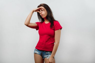 Genç, güzel bir kız burnunu kötü bir koku kapsar. Hafif bir arka plan üzerinde izole. Farklı insan duyguları, yüz ifadesi, tutum, algı, beden dili, tepki duyguları.