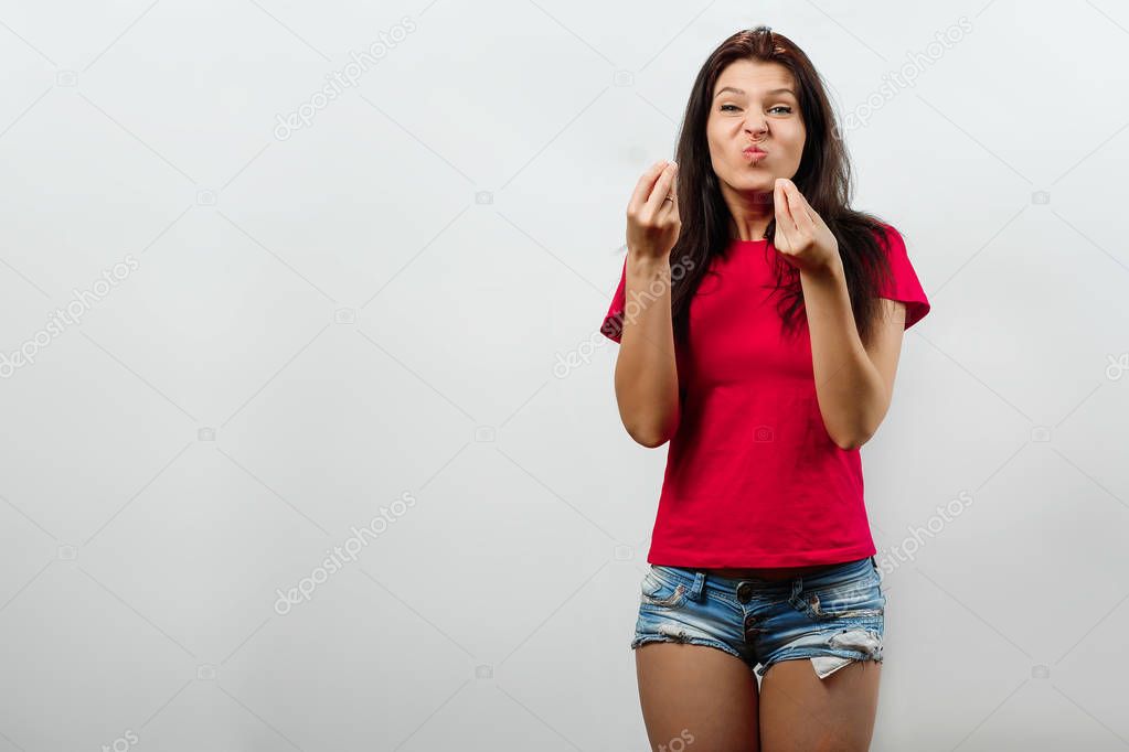 Young, beautiful girl shows an interrogative gesture with hands, an Italian gesture wtf. Isolated on a light background. Different human emotions,