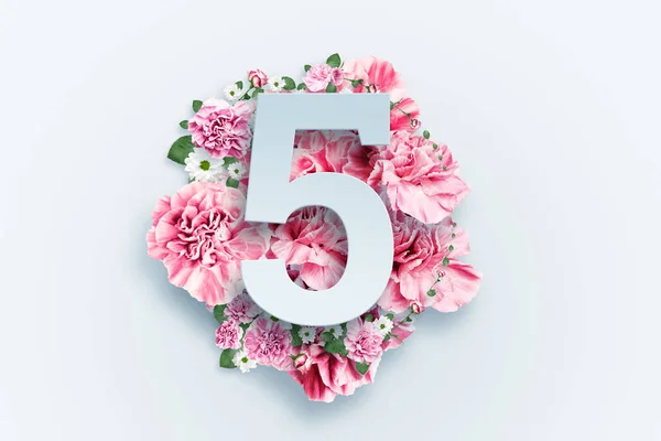En siffra på fem på en bakgrund av rosa blommor och gröna blad. Våren ljus bakgrund. Lägenheten låg, kopiera utrymme, blandteknik, ovanifrån. — Stockfoto