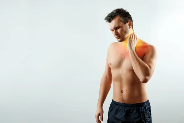 Vooraanzicht, de man heeft zijn handen achter de nek, de pijn in de nek in het rood gemarkeerd. Lichte achtergrond. Het concept van geneeskunde, fysiotherapie, massage en gezondheid. — Stockfoto