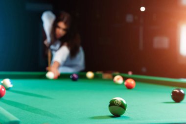 Genç güzel kız bilardo oynuyor. Karanlık arka plan. Keyifli zaman geçirme, dinlenme, eğlence.