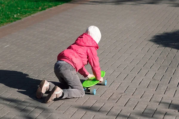 Pequena menina passeios de skate nas ruas da cidade no skate. Esportes infantis . — Fotografia de Stock