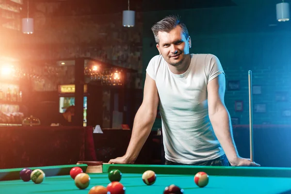 一个穿着白色T恤的男人在玩台球，一个深色的背景。快乐的消遣、娱乐、休闲、家庭假期、游戏. — 图库照片
