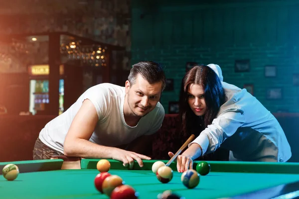 Bir adam ve güzel bir kız bilardo oynayan, bir adam bilardo oynamak için bir kız öğretiyor. Koyu arka plan. Keyifli eğlence, Aile dinlenme, eğlence, tatil.