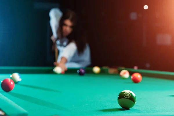 Jeune belle fille joue au billard. Fond sombre. Agréable passe-temps, repos, divertissement. — Photo