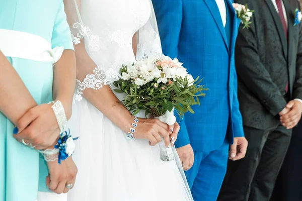 Uma vista de perto das mãos e do buquê de uma noiva com a festa nupcial no fundo. Conceito de casamento, relacionamento familiar, parafernália de casamento . — Fotografia de Stock