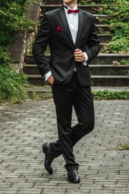 Sokak arkaplanında poz veren şık takım elbiseli damat..