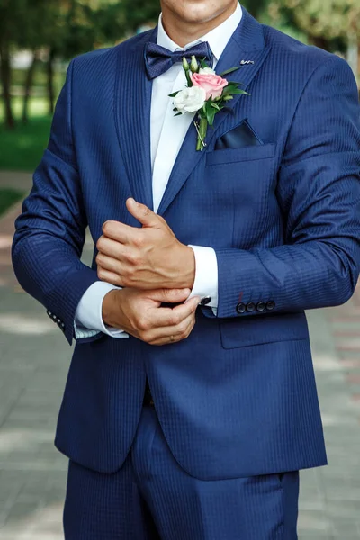 Noivo vestido com um terno elegante posando em um fundo de rua . — Fotografia de Stock