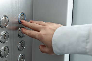 Kadın eli, parmak asansör düğmesine basar. Kariyer basamaklarını çık.