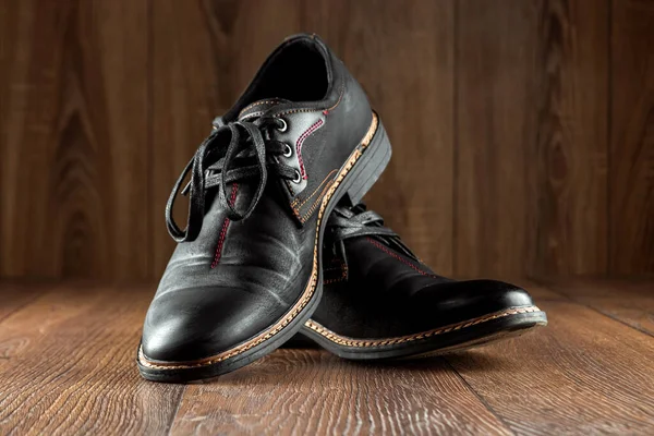 Black shoes one clean second dirty on a wooden background. The concept of shoe shine, clothing care, services.