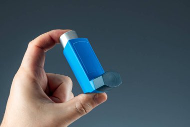 Close-up with an asthma inhaler in a male hand, asthmatic attack. The concept of treatment of bronchial asthma, cough, allergies, dyspnea.