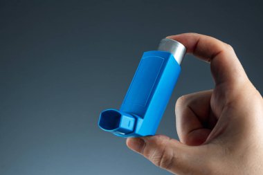 Close-up with an asthma inhaler in a male hand, asthmatic attack. The concept of treatment of bronchial asthma, cough, allergies, dyspnea.