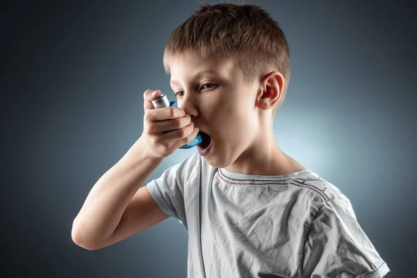 Portrait of a boy using an asthma inhaler to treat inflammatory diseases, shortness of breath. The concept of treatment for cough, allergies, respiratory tract disease. — 图库照片