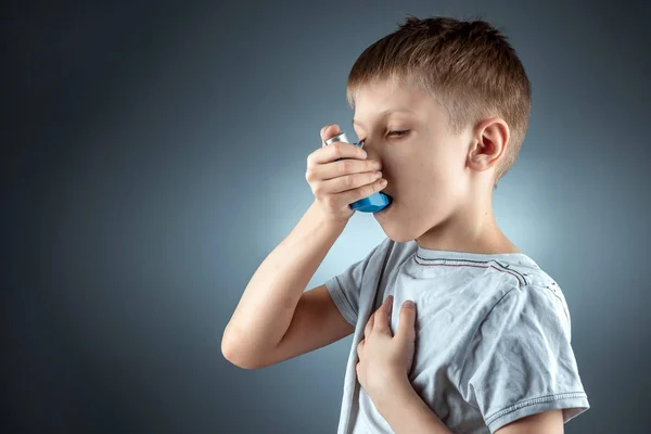 Portrait of a boy using an asthma inhaler to treat inflammatory diseases, shortness of breath. The concept of treatment for cough, allergies, respiratory tract disease. — ストック写真