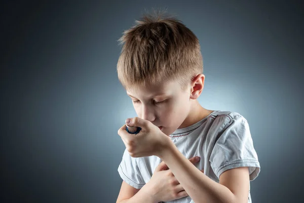 Portrait of a boy using an asthma inhaler to treat inflammatory diseases, shortness of breath. The concept of treatment for cough, allergies, respiratory tract disease. — ストック写真