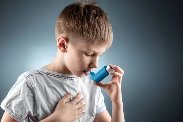 Porträt eines Jungen, der einen Asthma-Inhalator zur Behandlung entzündlicher Erkrankungen, Kurzatmigkeit einsetzt. das Konzept der Behandlung von Husten, Allergien, Atemwegserkrankungen. — Stockfoto